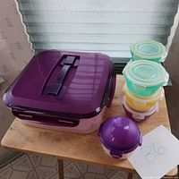 Closed large square container with purple lid, stacked small containers with pastel lids and one small purple container on side.