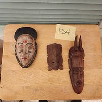 Three small African masks on wooden table, showing full set and variety in design