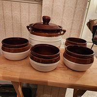 Angle view of soup crock with lid and four matching bowls showing brown and white ceramic color pattern.