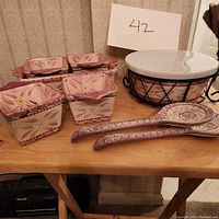 Overview photo showing 4 pink cranberry square ramekins arranged in square casserole, 2 spoon rests, large covered bowl with metal stand