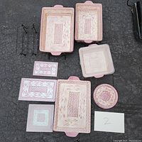 Photo showing the entire set of ceramic casseroles and trivets laid out on pavement.
