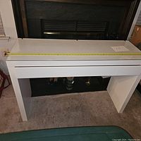 Front view of the white desk with glass top, showing the overall structure and design.