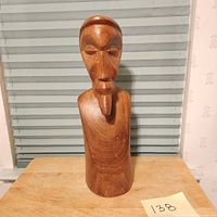 Full view of the statue showing the full bust on a table against blinds