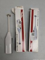 Two MITA electric mini stick mixers with packaging, showing a whisk attachment on one and mixer blade on the other, both in white, with product boxes showing branding and product info.