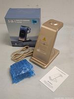 Photo of the 3-in-1 wireless charging station with USB cable and instruction manual, showing side view of the device and packaging box.