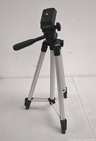 Front view of the aluminum camera tripod showing the mount, handle, and leg structure.