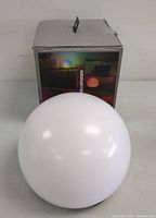 White spherical LED orb light in front of its retail packaging box showing colored lighting options.