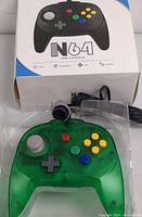 Top photo showing green transparent N64 controller in plastic tray with box behind it.