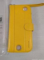 Closed view of bright yellow Moko wallet case with visible wrist strap and magnetic clasp, two circular cutouts on the back and 'moko' branding.