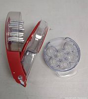 Red and clear plastic cherry pitter tool showing multiple metal rods with sharp tips used to remove pits from cherries.