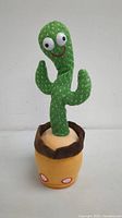 Front view of the green plush dancing cactus toy with googly eyes and smile in a yellow and brown fabric pot.