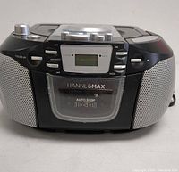 Front view of the HANNLOMAX portable CD player showing digital display, speaker grills, control buttons, and CD door with brand name and auto stop label.