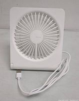 Front view of the white JISULIFE small desk fan with attached USB charging cable visible.