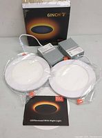 Two 6-inch LED recessed lights wrapped in plastic with two LED drivers and product packaging box in the background.