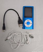 Top-down photo showing blue MP3 player, black USB to micro-USB cable, and white wired earbuds on light surface.