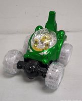 Front view of the green kids ride-on car with clear wheels and no lights on.