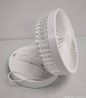 White folding fan partially folded in base, USB charging cable visible.
