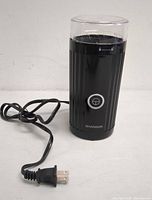 Front view of the Shardor black electric coffee grinder showing power cord and front button with coffee cup icon.