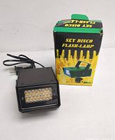 Front view of the Sky Disco Flash Lamp showing the 24 LED bulbs and the power cord coiled beside the lamp, along with its original box.