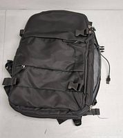Top front view showing multiple zipper compartments and exterior buckle straps on black backpack