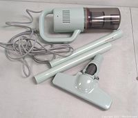 Vacuum cleaner body with power cord laid out alongside two extension tubes and floor cleaning attachment, shown from a top angle.