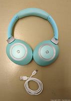 Top view of green wireless headphones with USB charging cable laid below.