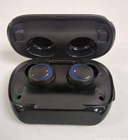 Photo of black wireless earbuds seated inside the open charging case showing earbud design and LED status lights.