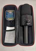 Bonnok wireless karaoke microphone placed inside custom carrying case, showing foam windscreen, control panel, and internal mesh pocket with included paperwork.