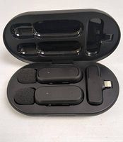 Open charging case showing two wireless lapel microphones with foam covers, and connectors inside molded slots.