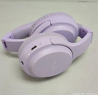 Folded pastel purple SIMPAR Bluetooth headphones showing charging port and soft padded ear cups.
