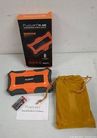 Fuzion FU-200 digital scale alongside packaging box, warranty card, two batteries, and golden-yellow storage pouch on a white surface.