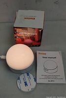 Photo showing Kintion LED night light, box, user manual, and 3M adhesive pad on a gray surface.