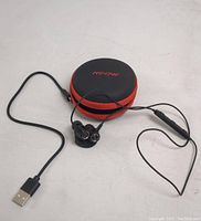 MPOW Bluetooth earphones with inline control and magnetic earbuds alongside zipped carry case, displayed on white surface