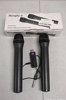 Photo of two black handheld microphones with foam grills, accompanied by a small USB wireless receiver and the original box showing the model V16U smart wireless microphone.