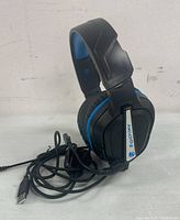 Front view of black and blue wired gaming headphones with USB cable and microphone