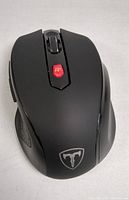 Top-down view of wireless black computer mouse showing scroll wheel, DPI button, and red LED light with a logo at the bottom.