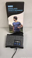 Box and wireless sports headwear set on display, showing front of box with runner and actual product with control panel visible.