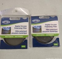 Two Optex Digital Circular Polarizing Filters in original packaging, showing front packaging details and product branding.