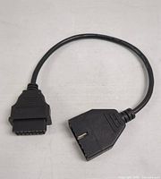 Photo showing OBD1 male connector on one end of the short black cable and OBD2 female connector on the other end, capturing front view of cable connectors.