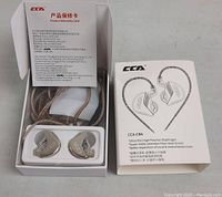 Image showing open box of CCA CRA headphones with inserted wired earphones and product warranty card.