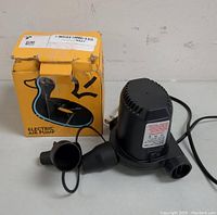 Black electric air pump alongside original yellow box showing wear and tear.