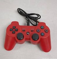 Front view of red PS3 Mario Retro wireless controller showing buttons, analog sticks, and USB cable