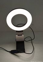 Clip-on selfie ring light illuminated and clipped to surface, showing circular LED light and clip mount.
