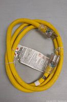 Photo of the coiled yellow electrical cord with clear ends and attached tag with instructions.