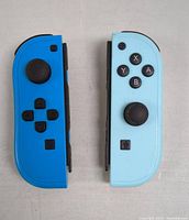 Photo of the blue and light blue Nintendo Switch Joy-Con controllers showing front and side button layouts.