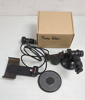 Overview of phone holder components including adjustable holder with wired charger, suction cup mount, suction base, and labeled box.