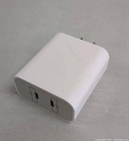 Photo of the white PD 20W USB-C power adapter showing the USB-C output port and prongs for power connection.