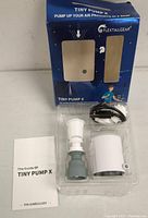 Clear plastic tray with Tiny Pump X air pump, nozzle attachment, charging cable, instruction manual, and blue retail box.