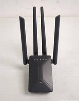 Top angle showing four long external antennas and LED indicators on the front panel of the black Wi-Fi extender.