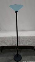 Full view of black metal floor lamp with blue frosted ribbed glass shade.